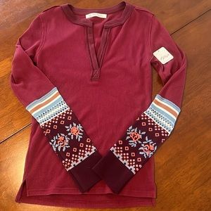 Burgundy waffle material with v notch collar. Bottom half of sleeves are knit.